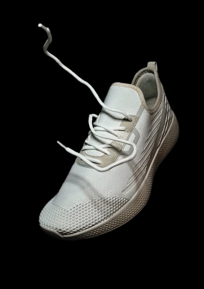 Close-up of a white sports shoe against a black background showcasing footwear design.