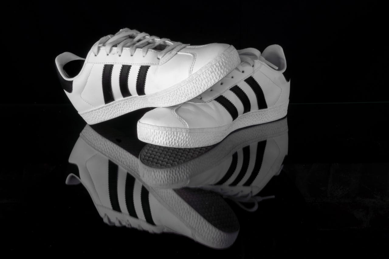 Stylish black and white sports shoes displayed on a reflective surface, emphasizing sleek design.